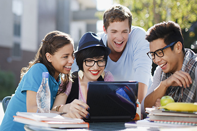 smiling group of college student reading about time savings tricks on laptop